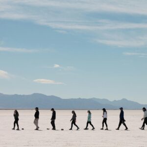 A group of people walking across the vast Salinas Grandes salt flats in Jujuy, Argentina.