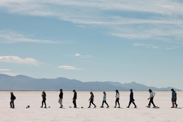 A group of people walking across the vast Salinas Grandes salt flats in Jujuy, Argentina.