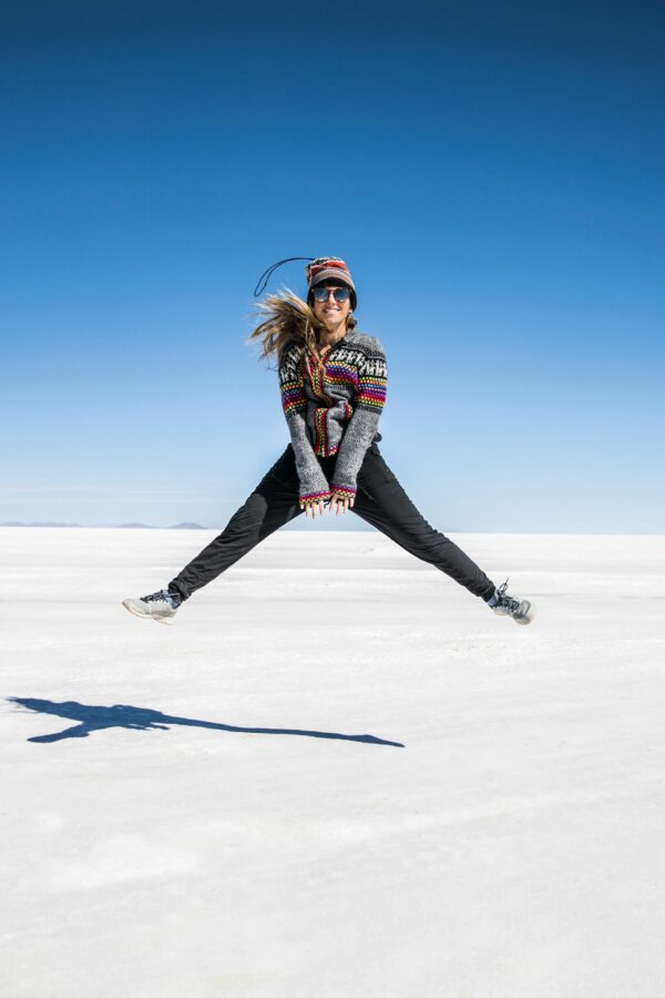 Woman jumping joyfully on the vast white expanse of Bolivia's Salar de Uyuni.